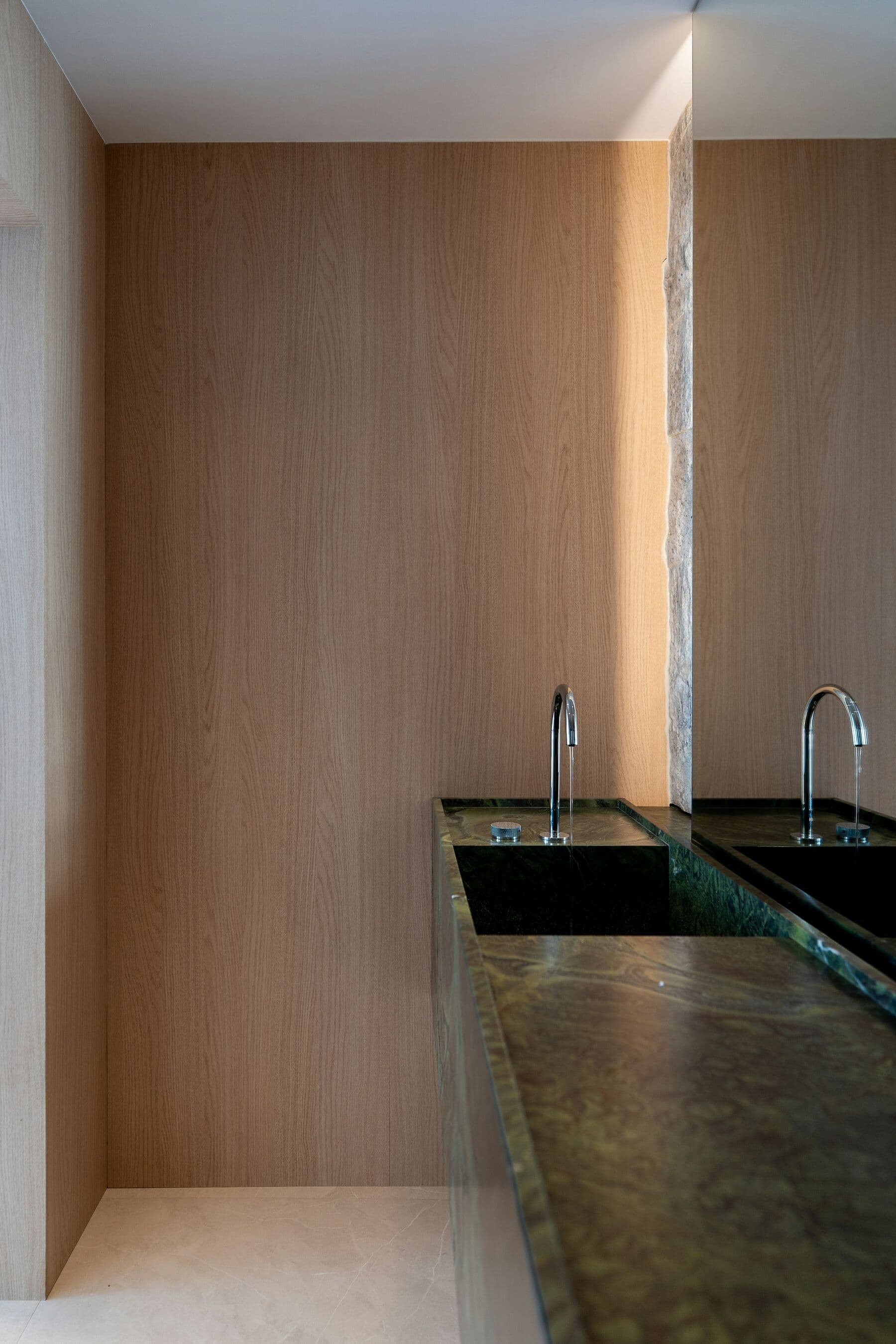 Salle de bain habillée de chêne du sol au plafond, avec un plan en marbre vert.
